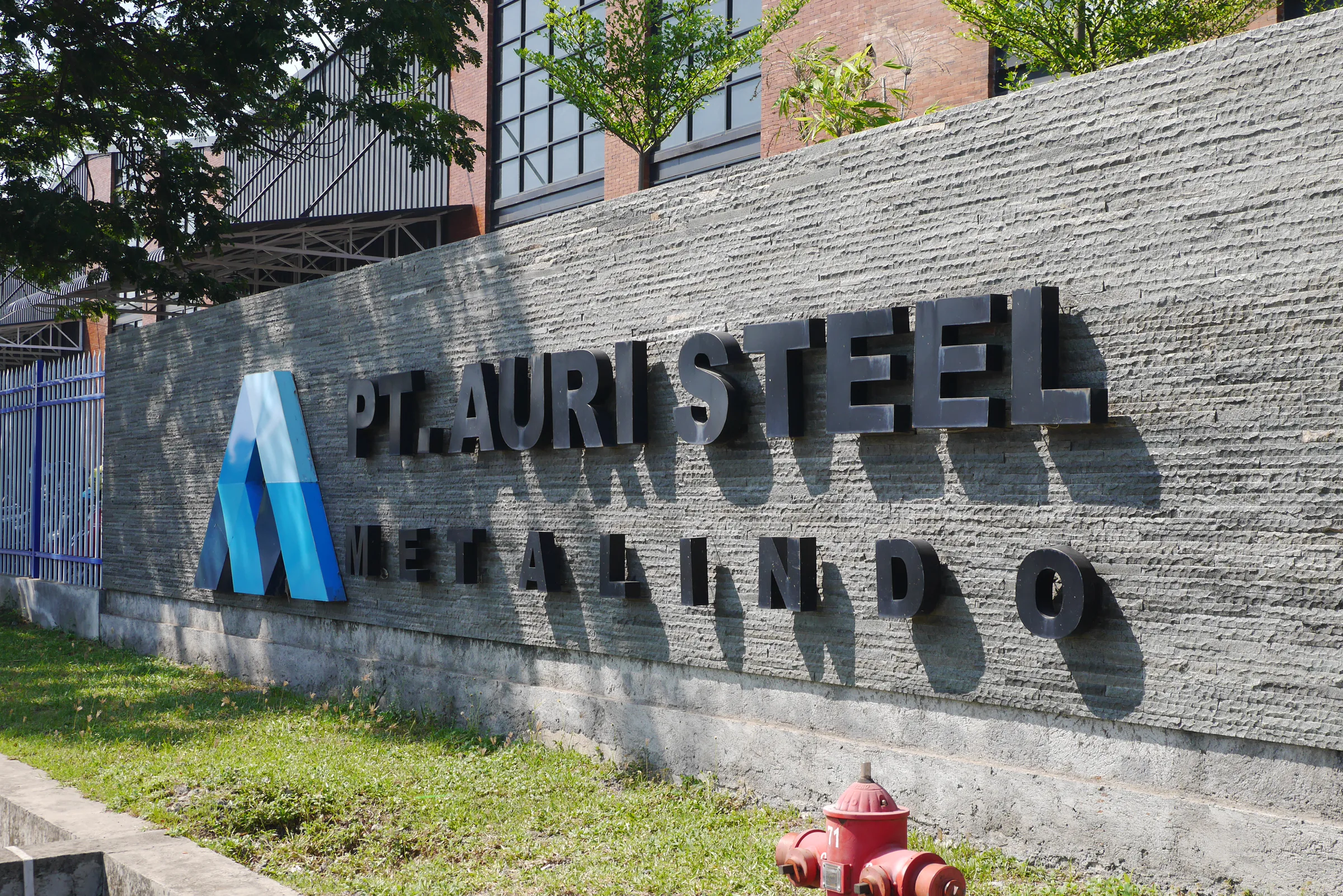 Fasilitas manufaktur baja dengan panel surya, area hijau, dan pengelolaan air
